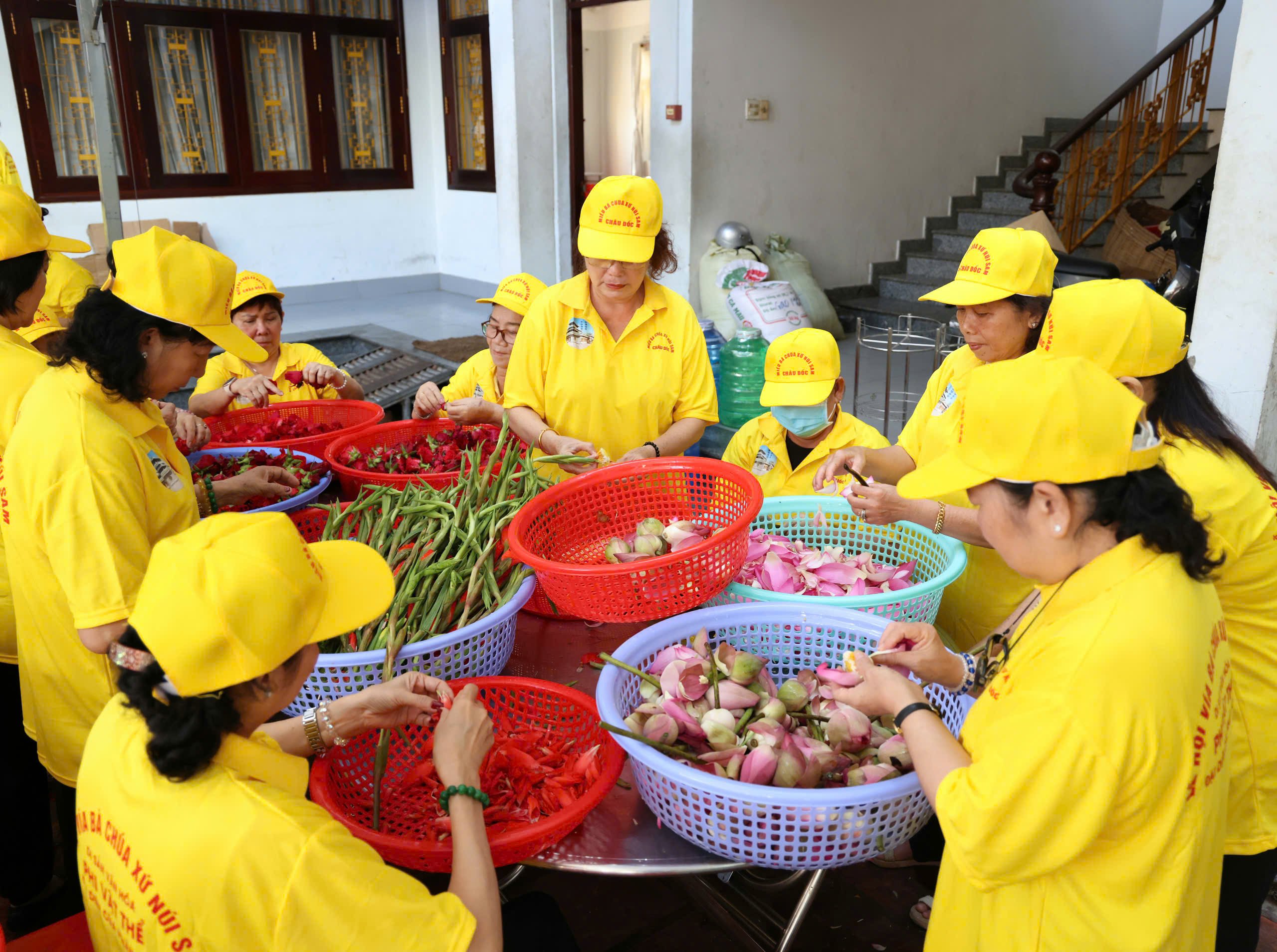 Trong trang phục chỉnh tề được Ban Quản trị lăng miếu núi Sam chuẩn bị, mọi người bắt đầu phân công các công việc như rửa hoa, tách cánh hoa, nhóm lửa,...