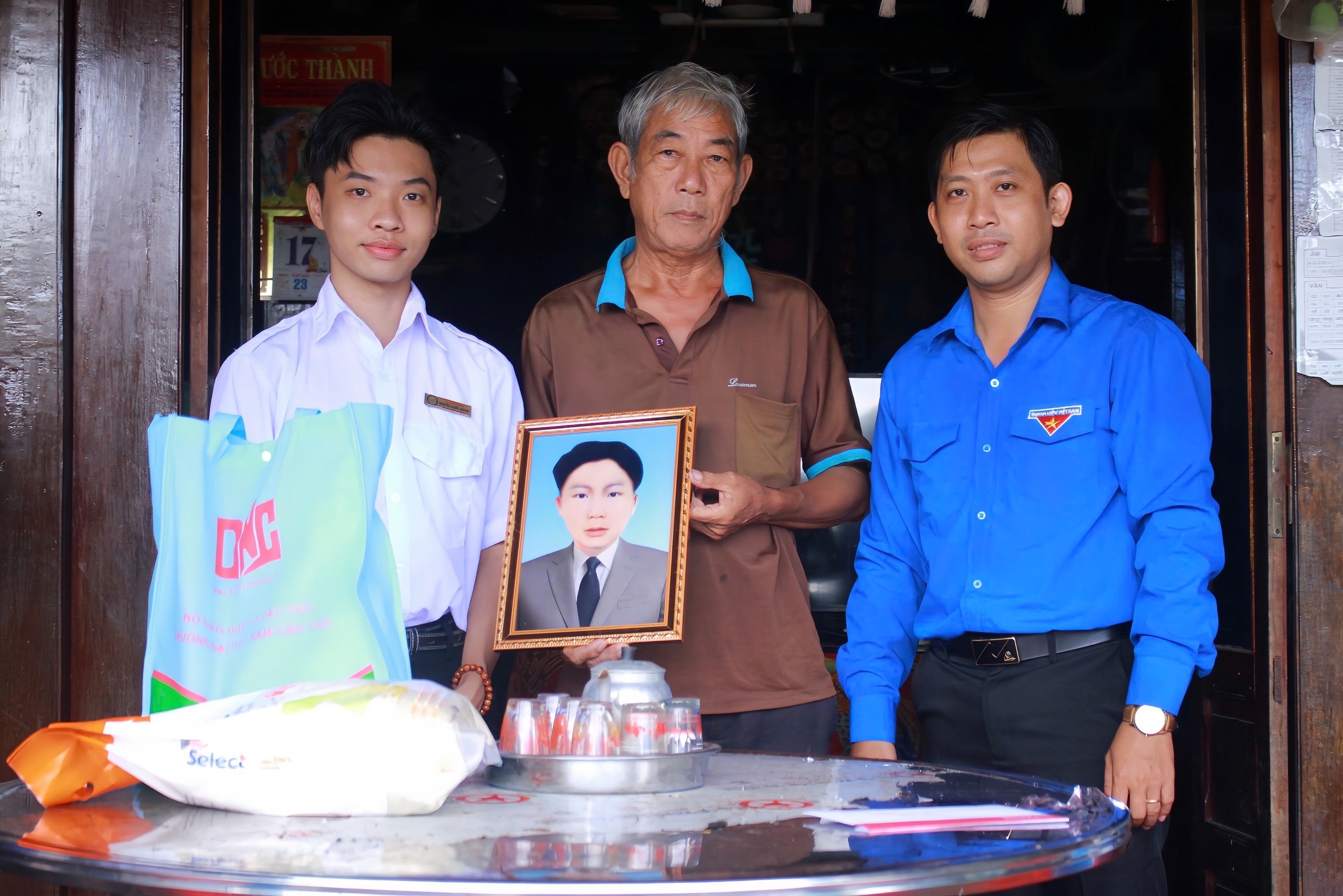 Anh Đỗ Hữu Ân (bìa phải) - Bí thư Đoàn phường Mỹ Ngãi và bạn Nguyễn Quốc Khang - Chỉ huy Trưởng chiến dịch trao ảnh được phục dựng cho thân nhân Liệt sĩ.
