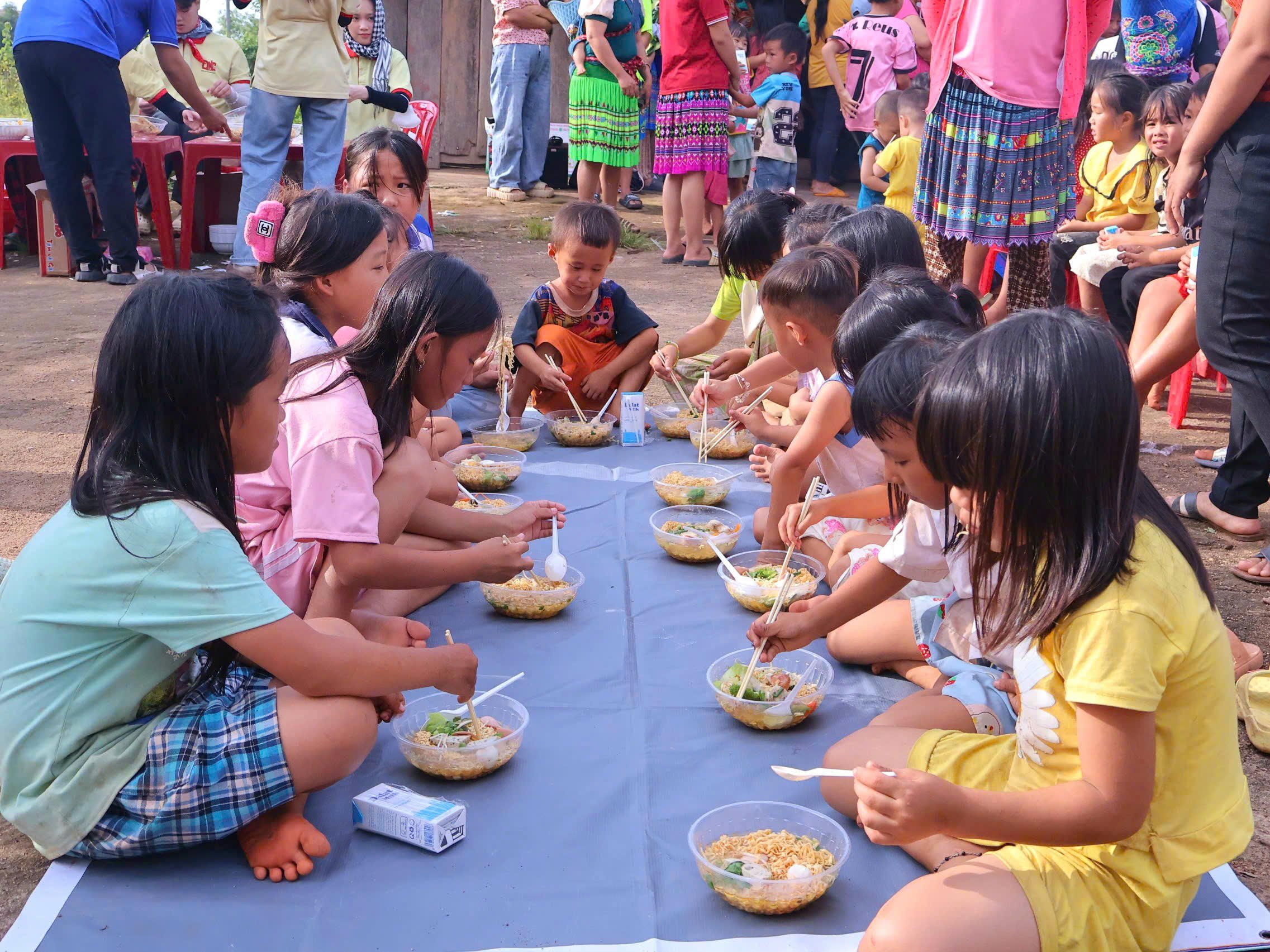 Khi nhận những tô mì từ tay tình nguyện viên, các em bé nở nụ cười rạng rỡ, ánh mắt sáng lên niềm hạnh phúc.