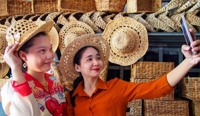 Khách hàng thích thú chụp hình với các mặt hàng thủ công mỹ nghệ do phụ nữ câu lạc bộ làm ra.