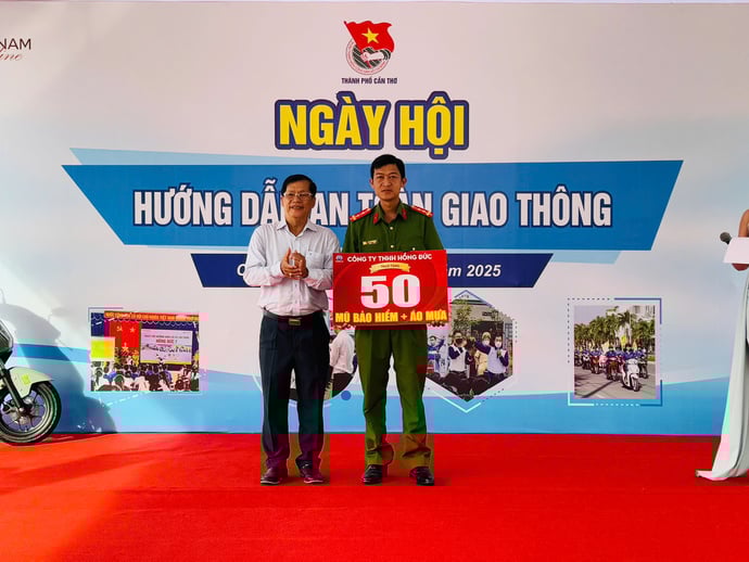 Ông Nguyễn Tùng Phương - Phó Giám đốc Công ty TNHH Honda Hồng Đức trao bảng tượng trưng 50 mũ bảo hiểm và 50 áo mưa cho đội ngũ lực lượng công an phường Tân An.