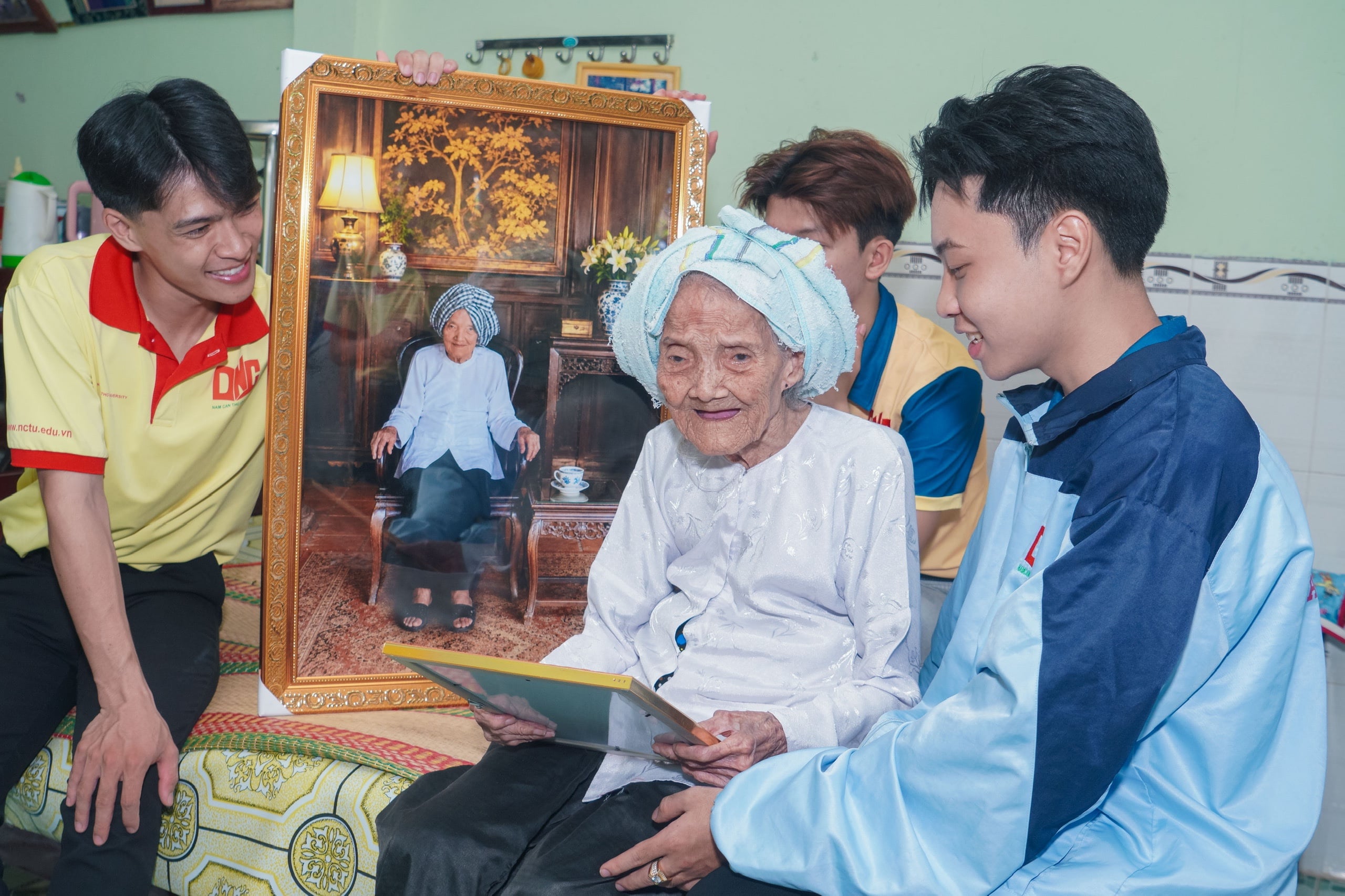 Mẹ Việt Nam Anh hùng Nguyễn Thị Nghiệp, 99 tuổi và các bạn sinh viên vui vẻ bên hình ảnh vừa được phục dựng.