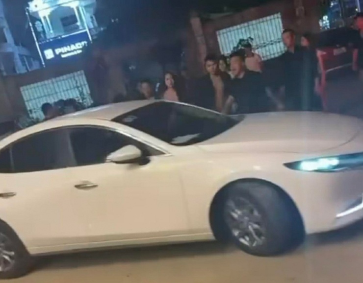 Tài xế lái ô tô cán qua chân người đàn ông đứng giữa đường. Ảnh cắt từ clip
