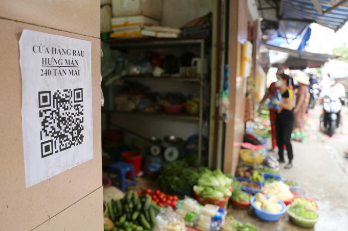 Mã QR code được dán trước cửa một cửa hàng rau tại chợ phục vụ người dân khai báo y tế.