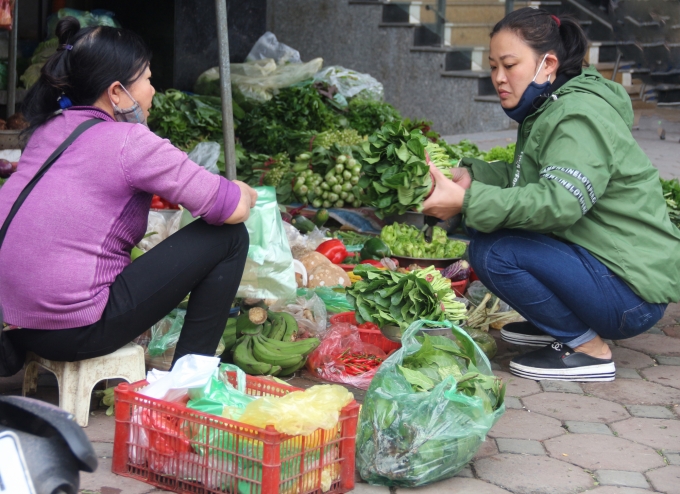 Người tiêu dùng Hà Nội căn đong lưỡng lự khi đi mua rau. (Ảnh: Phạm Hiếu).