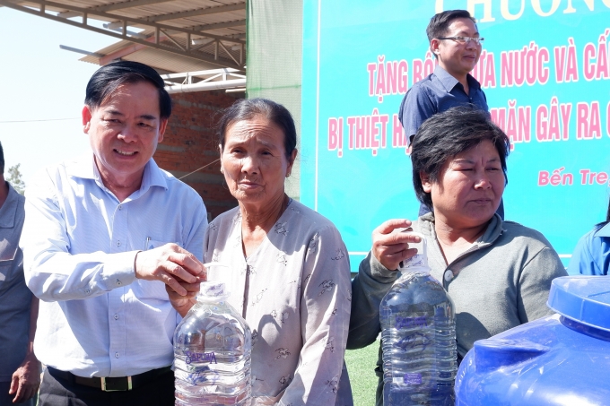 Phó Bí thư Thường trực Tỉnh ủy Trần Ngọc Tam trao bình nước ngọt cho các hộ dân. Ảnh: Minh Mừng.