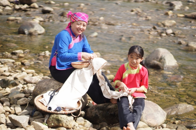Chị Sùng Thị Lan (phải) buộc sỏi để chuẩn bị nhuộm vải. Ảnh: TL.