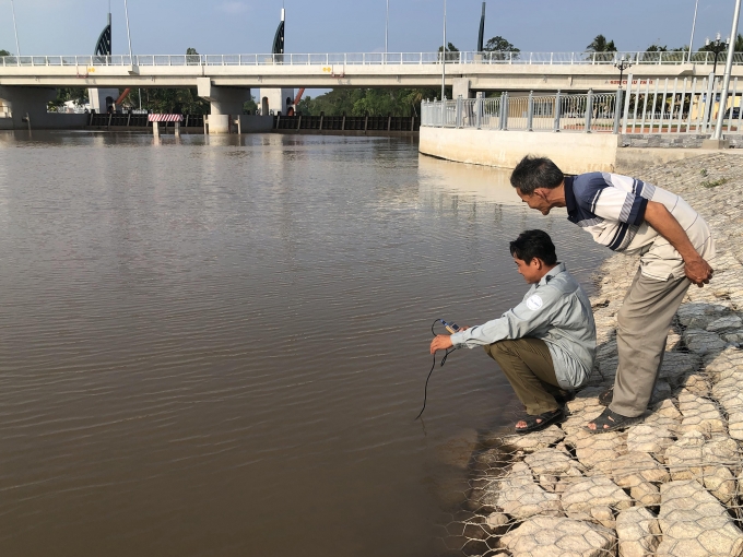 Nhân viên cống Tân Dinh và nông dân kiểm tra độ mặn nước sông. Ảnh: Sáu Nghệ.