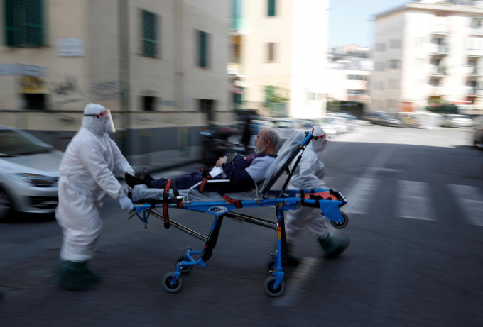 Nhân viên y tế mặc đồ bảo hộ vận chuyển một bệnh nhân trên cáng ở Naples, Italy. Ảnh: Reuters.