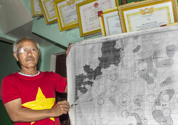 Ngư dân Huỳnh Văn Minh với tờ hải đồ có khoanh vô số cung tròn, đánh dấu điểm cá.