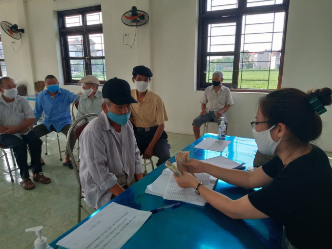 Người dân huyện Thường Tín nhận tiền hỗ trợ từ gói hỗ trợ an sinh xã hội 62.000 tỷ đồng do ảnh hưởng dịch Covid-19. Ảnh: Trần Hồ.