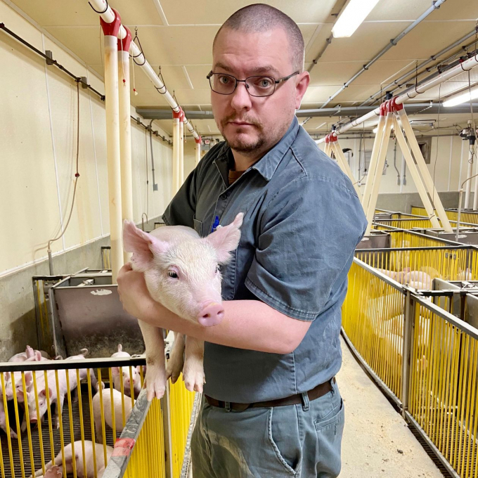 Kevin Turner bế một con lợn con tại trang trại dành để dạy chăn nuôi ở Đại học bang Michigan. Ảnh: WSJ.