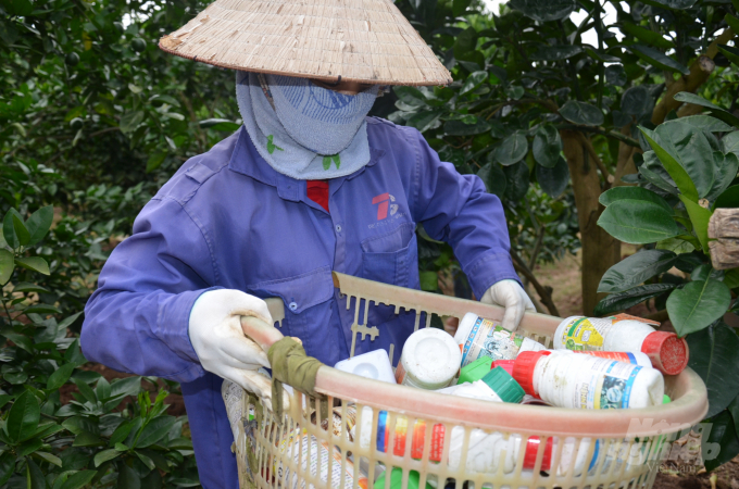 Một chủ vườn ở huyện Lục Ngạn, tỉnh Bắc Giang đang khệ nệ bê rổ vỏ thuốc BVTV dùng trong mấy tháng. Ảnh: NNVN.