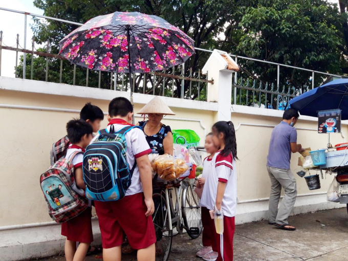 Nhóm học sinh Trường Tiểu học Hồng Hà (Quận Bình Thạnh) mua bánh tráng trộn để ăn trong lúc chờ ba mẹ đến đón về. Ảnh: Thùy Lâm.