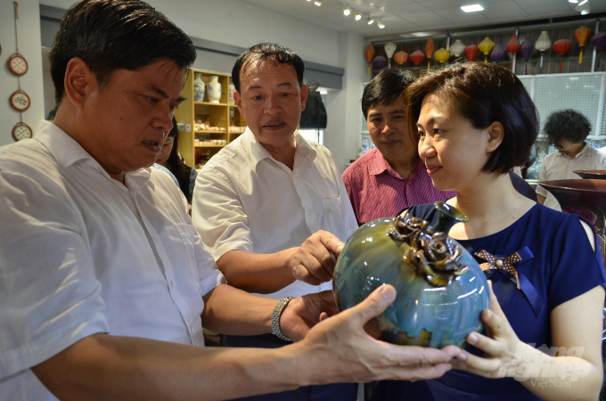 Thứ trưởng Bộ NN-PTNT Trần Thanh Nam xem 1 sản phẩm OCOP tại làng gốm sứ Bát Tràng. Ảnh: NNVN.