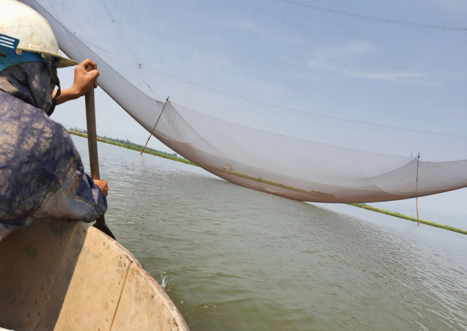 Bơi thuyền thúng đến giàn rớ phải mang áo mưa để khỏi ướt do nước từ lưới rụng xuống. Ảnh: N.Tâm.
