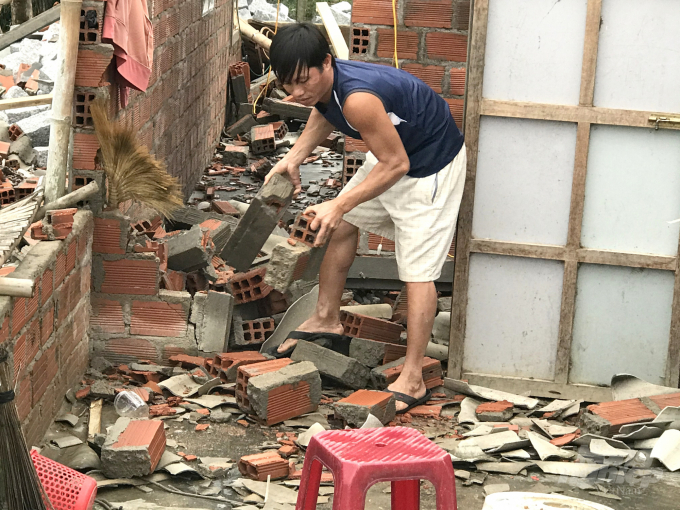 Anh Nguyễn Minh Khoa dọn dẹp căn nhà vừa bị sập trong cơn bão số 9. Ảnh: Vũ Đình Thung.