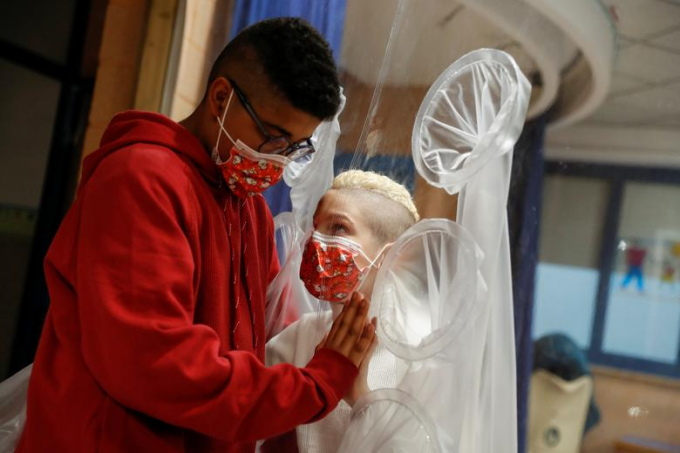 Một đứa trẻ nhiễm Covid-19 nhập viện được gặp bạn thân thông qua một lớp bảo vệ bằng ni lông ở bệnh viện San Raffaele, Rome, Italy ngay trước lễ Giáng sinh hôm 22/12/2020. Ảnh: NYP