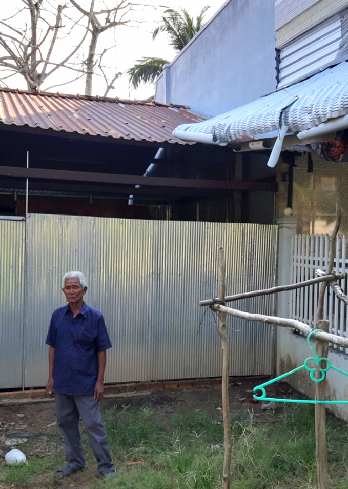 Ông Trần Văn Chính đứng ở sân căn nhà tình nghĩa, có mái tôn từ nhà ông Khương chìa sang hơn một mét