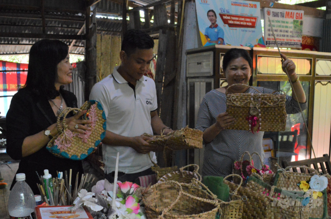 Bà Thu - vợ ông Phương đang giới thiệu về sản phẩm túi xách được đan bằng lá cây bồn bồn. Ảnh: Trung Chánh.