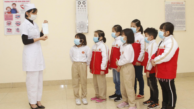 Cán bộ Y tế hướng dẫn các em học sinh đeo khẩu trang đúng cách để phòng dịch Covid-19. Ảnh: Việt Thắng.