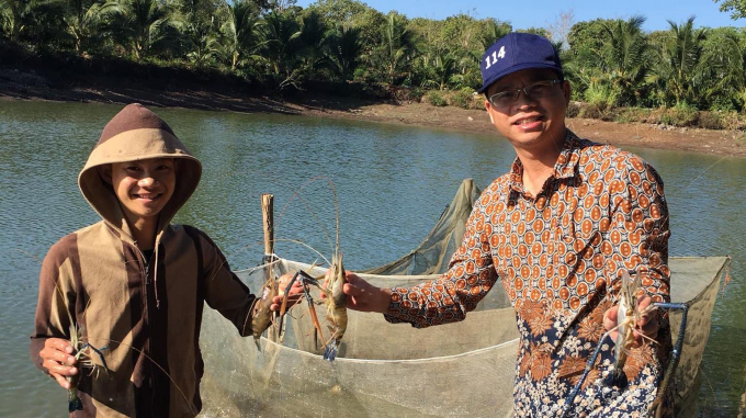 Anh Thành (bên trái) giới thiệu tôm càng xanh cho khách hàng đến mua. Ảnh: T. Dũng.