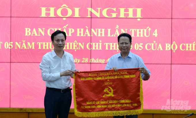 Ông Lại Xuân Lâm (trái) - Phó Bí thư Đảng ủy Khối các cơ quan Trung ương trao cờ thi đua cho Đảng bộ Cục Quản lý xây dựng công trình. Ảnh: Bảo Thắng.