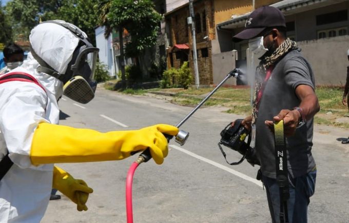 Nhiếp ảnh gia Lakruwan Wanniarachchi của AFP được nhân viên y tế sát khuẩn khi tác nghiệp tại Colombo (Sri Lanka), ngày 31/3/2020. Ảnh: AFP.