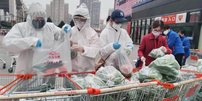 Các tình nguyện viên và nhân viên công tác cộng đồng đeo khẩu trang phân loại và đóng gói thực phẩm tại một siêu thị ở Vũ Hán hồi tháng 2/2020. Ảnh: Reuters.