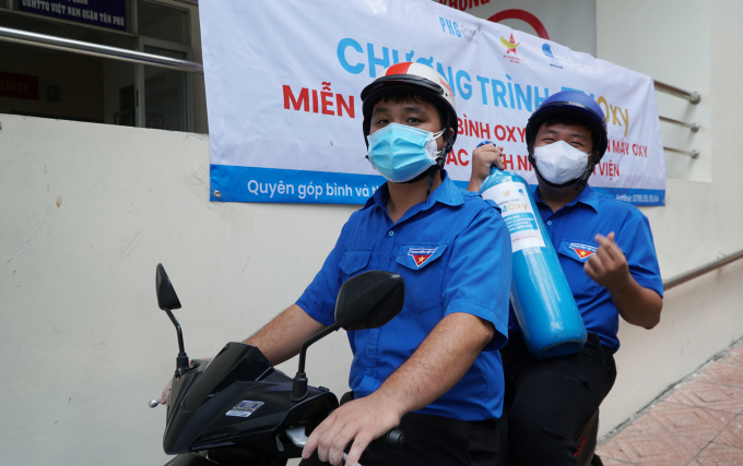 Tình nguyện viên chở bình oxy bằng xe máy tới khu vực phong tỏa.