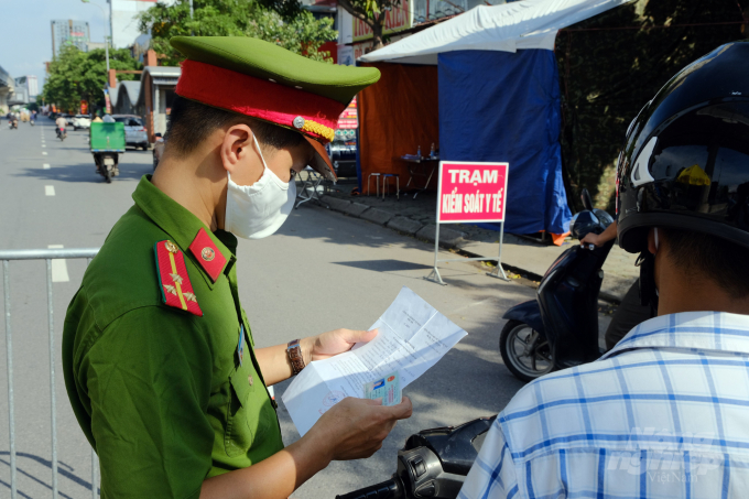 Cảnh sát kiểm tra giấy đi đường của người dân tại chốt kiểm soát trên đường Mai Dịch. Ảnh: Bảo Thắng.