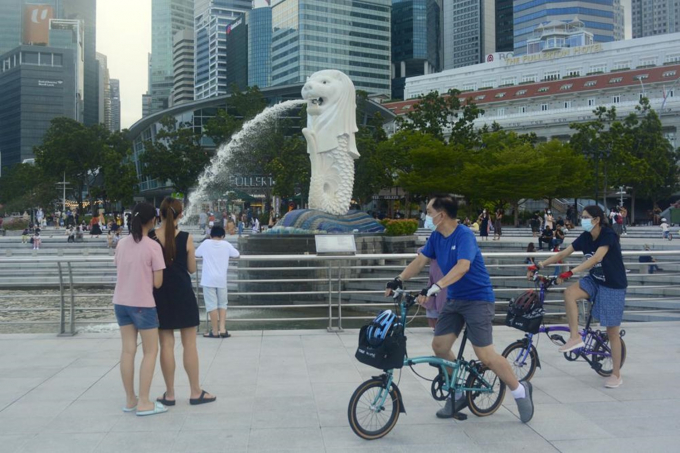 Người dân đạp xe, đi dạo gần tượng Merlion, một trong những điểm thu hút khách du lịch của Singapore, hôm 26/9. Ảnh: AP.