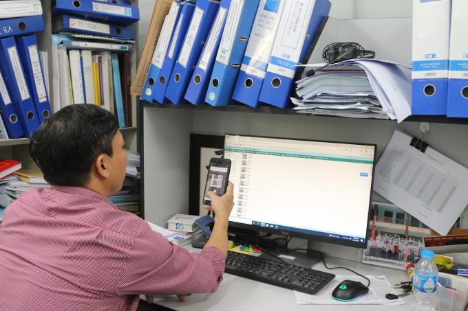 Thạc sĩ Trương Văn Minh trực tiếp dùng điện thoại thông minh quét mã QR-code kiểm tra sự hợp lệ của các thủ tục hành chính. Ảnh: Đinh Mười.