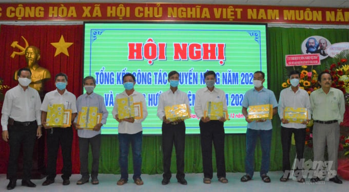Tổng Giám đốc Công ty TNHH Xuân Phương Kiên Giang (bìa trái) cùng Giám đốc Trung tâm Khuyến nông Kiên Giang tặng quà cho các nông dân tham gia xây dựng phát triển cánh đồng lớn hiệu quả trong năm 2021. Ảnh: Trung Chánh.