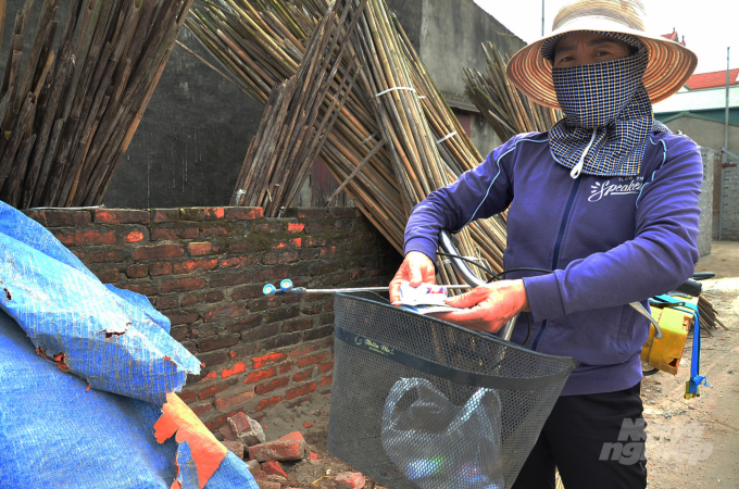 Chị Nguyễn Thị Mến đang cầm trên tay hai lọ thuốc sâu Tàu, nhập lậu chuẩn bị đi phun. Ảnh: Dương Đình Tường.