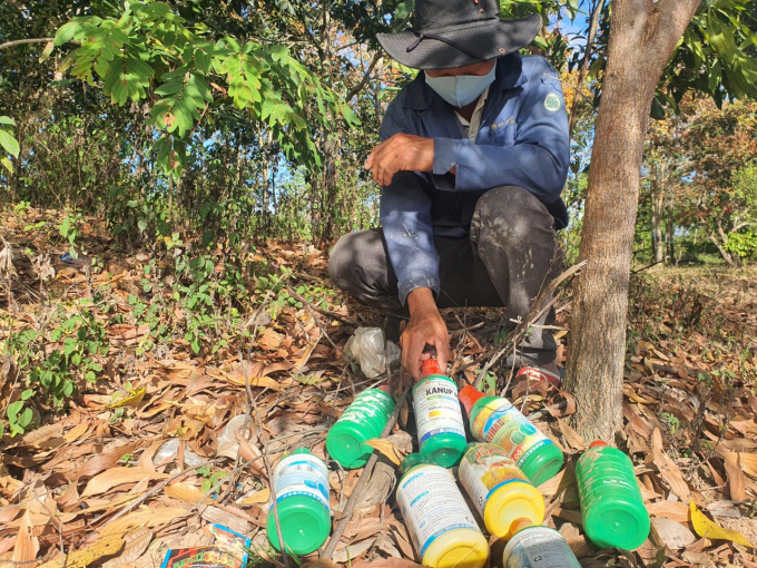 Village chief Y Tim Eban of Ea Rok village next to piles of pesticide bottles and packages. Photo: Hoang Anh.