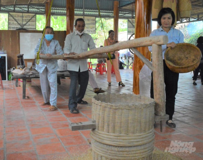 Nhiều người thích thú tham gia trải nghiệm xay lúa bằng cối xay thủ công xưa tại trang trại lúa mùa Tư Việt. Ảnh: Trung Chánh.