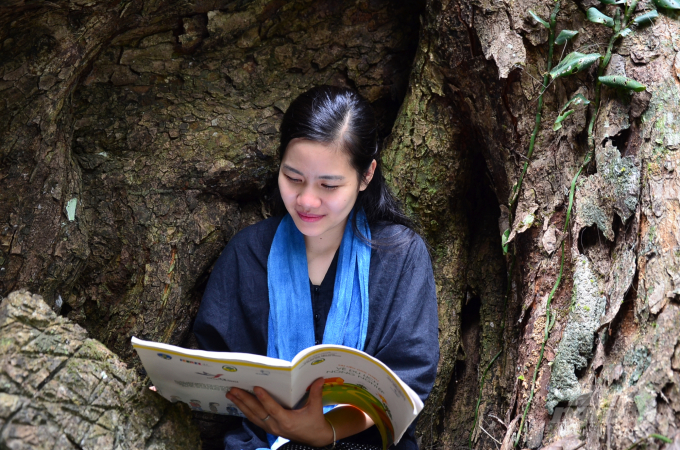 Nguyễn Thị Cẩm Ly - Giám đốc HTX Cam sành Sơn Nữ đọc sách để tĩnh tâm dưới một hốc cây. Ảnh: Dương Đình Tường.