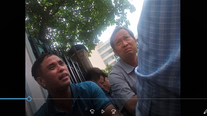 Ông Thiết (bên trái) tại quán trà đá bên ngoài trụ sở ngân hàng MSB (ảnh cắt từ clip).