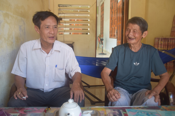 นาย Lam Van Xuan (ปกขวา) และนาย Nguyen Ngoc Son เลขาธิการพรรคเซลล์และหัวหน้าหมู่บ้าน An Thai นั่งสนทนา  รูปถ่าย: VDT