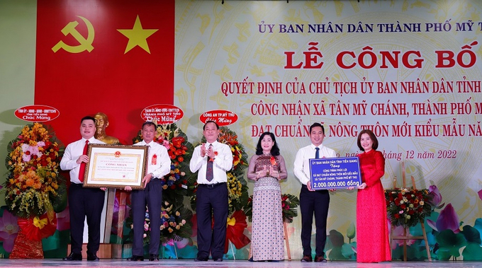 Ông Nguyễn Văn Vĩnh - Chủ tịch UBND tỉnh Tiền Giang trao quyết định công nhận xã Tân Mỹ Chánh đạt chuẩn nông thôn mới kiểu mẫu. Bà Châu Mỹ Phương, Trưởng Ban Tuyên giáo Tỉnh uỷ trao số tiền thưởng 2 tỷ đồng. Ảnh: Minh Đảm.