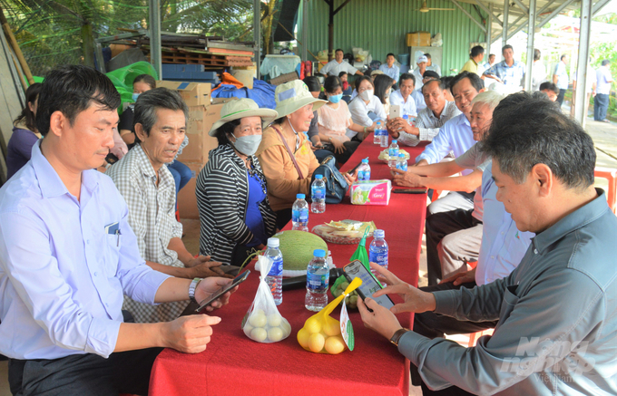 Giám đốc Trung tâm Khuyến nông Quốc gia Lê Quốc Thanh (hàng đầu bên phải) tham quan trang trại kinh tế tuần hoàn của Công ty Ngũ Thường Mekong và dùng điện thoại quét mã QR code để kiểm tra quy trình sản xuất. Ảnh: Trung Chánh.