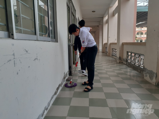 Học sinh làm vệ sinh trước khi vào lớp học trong ngày đầu tiên đi học trở lại. Ảnh: Hoàng Vũ.