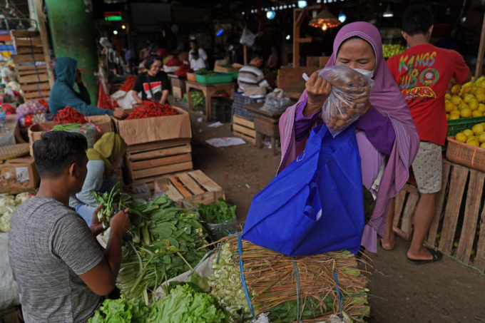 Một người dân nghèo mua rau tại chợ đầu mối Pasar Induk Kramat Jati ở thủ đô Jakarta, Indonesia hôm 26 tháng 2 năm 2022. Ảnh: Bloomberg.