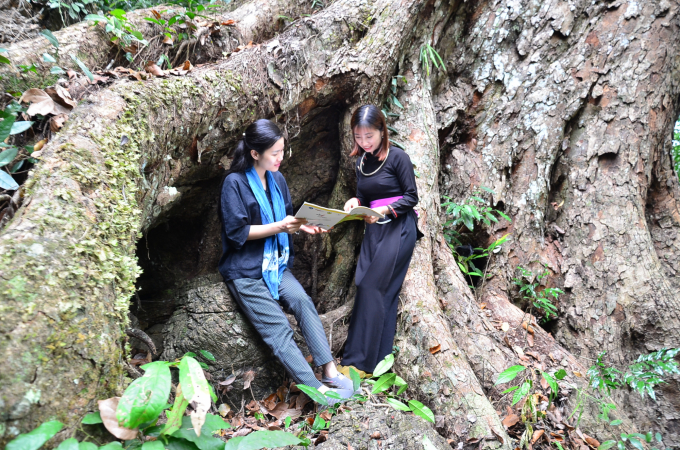 Nguyen Thi Khiet, a freelance tour guide in Na Hang (right) and Nguyen Thi Cam Ly - Director of Son Nu Cam Sanh Cooperative (left) reading a book to unwind under a tree. Photo: Duong Dinh Tuong.