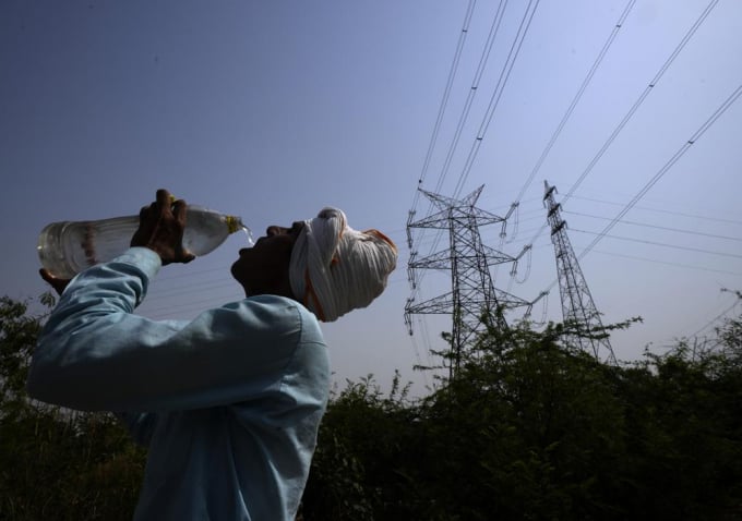 A workers quenches his thirst next to power lines as a heatwave continues to lashes the capital, in New Delhi, India, Monday, May 2, 2022. An unusually early and brutal heat wave is scorching parts of India, where acute power shortages are affecting millions as demand for electricity surges to record levels. Photo: AP/Manish Swarup