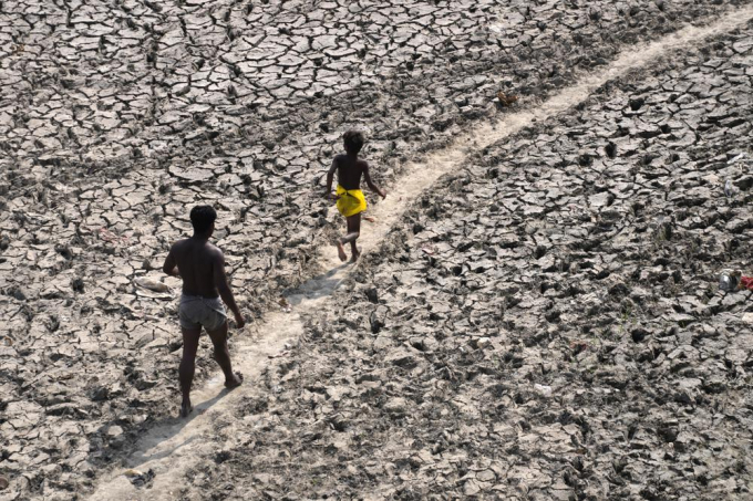 A man and a boy walk across an almost dried up bed of river Yamuna following hot weather in New Delhi, India, Monday, May 2, 2022. An unusually early and brutal heat wave is scorching parts of India, where acute power shortages are affecting millions as demand for electricity surges to record levels. Photo: AP/Manish Swarup