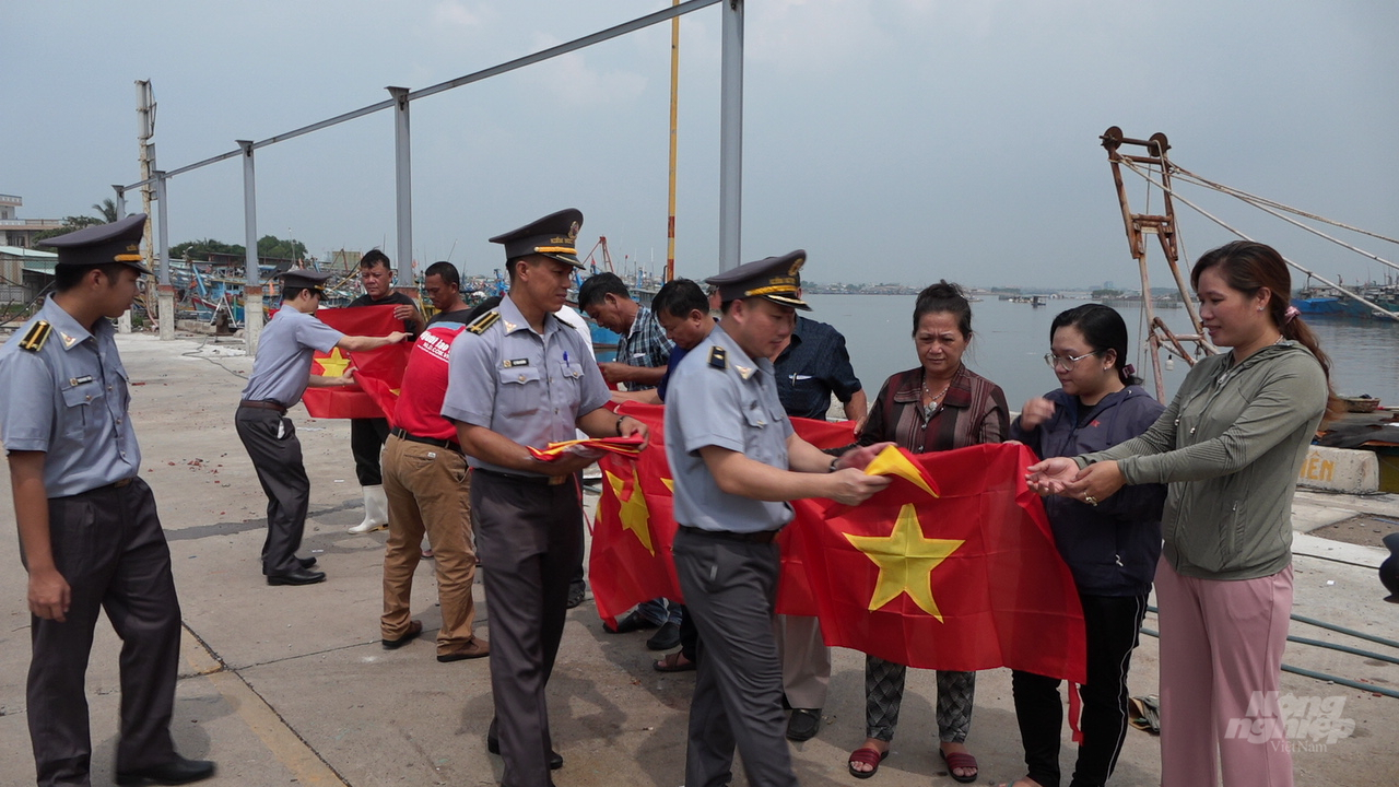 Đoàn công tác của Cục Kiểm ngư và Báo Người Lao Động tặng cờ cho các chủ tàu cá, ngư dân  cảng cá Hương Phước. Ảnh: Minh Sáng.