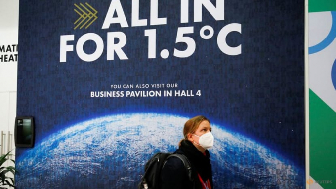 A delegate walks past a climate change poster at the UN Climate Change Conference (COP26) in Glasgow, Scotland, Britain, November 1, 2021. Photo: RT
