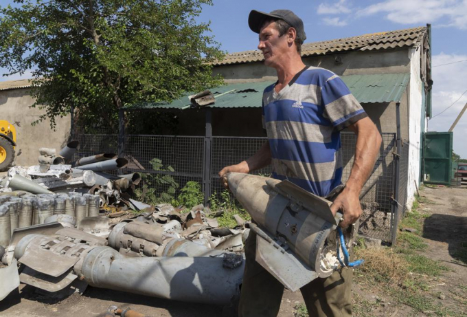 Một nông dân Ukraine thu gom đầu đạn rocket trên cánh đồng lúa mì của gia đình cách vùng Dnipropetrovsk chừng 10 km hôm 4/7/2022. Ảnh: AP